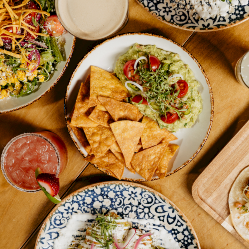 A table of colorful bowls and plates of Asian dishes, chopsticks, and shared food in a cozy meal setting, inviting and vibrant.