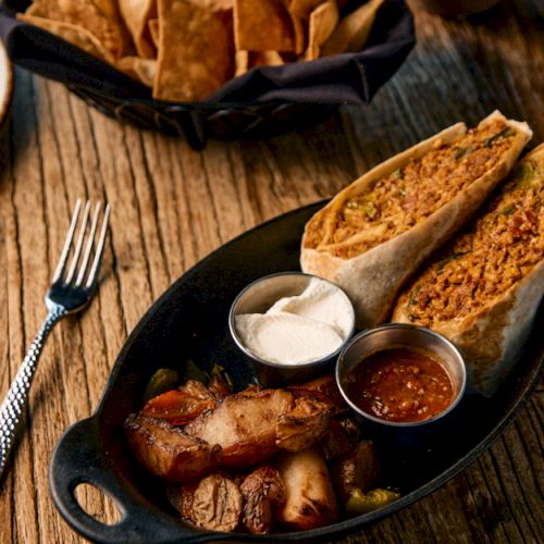 Slices of crusty bread with butter and a bowl of creamy sauce on a wooden table.
