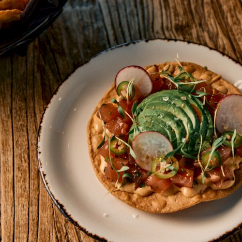 A small bowl of dumplings or noodles topped with herbs on a wooden table, likely an Asian-inspired dish. Top it at 140 characters, always ending the sentence.