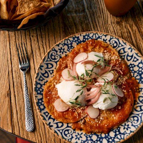A small pizza with pepperoni and cheese on a wooden table.