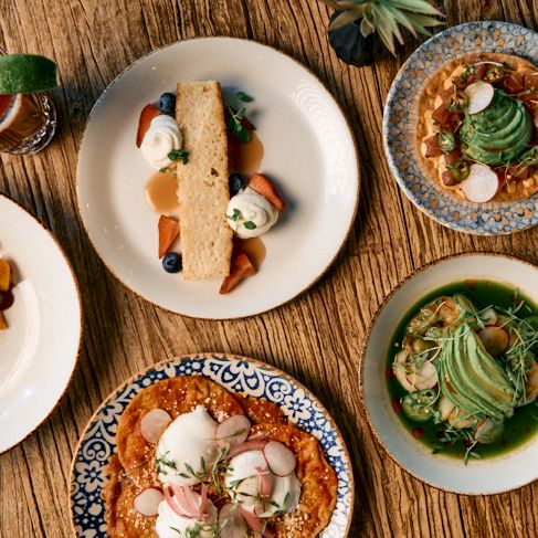 A colorful plate of assorted dishes with salads and dips, arranged in small bowls around a central plate.