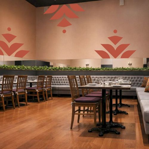 A cozy library or cafe with warm lighting, wooden tables, and bookshelves; red leaf wall art adds a welcoming vibe.